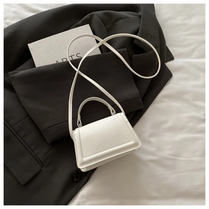 Close-up of white leather mini handbag with top handle and fine stitching details