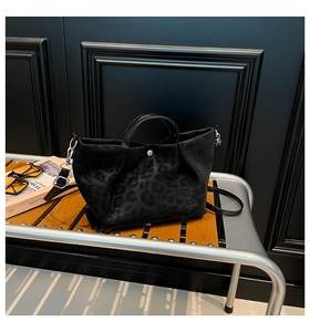 Detail view of the black suede tote with subtle leopard print and silver snap button closure