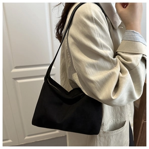 Close-up of minimalist black nylon underarm bag with gold zipper and smooth texture
