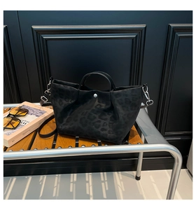 Macro view of black leopard print tote bag with silver buckle on a wooden bench