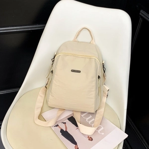 Detail of light beige water-resistant nylon mini backpack with multiple zipper pockets