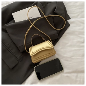 Macro detail of a mini golden crossbody bag showing metallic texture and size reference