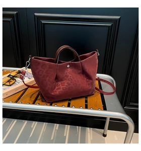 Macro view of burgundy leopard print nylon tote with leather handles and silver buckle
