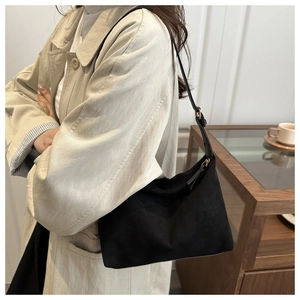 Close-up of black matte hobo bag on model wearing beige trench coat in cozy home setting