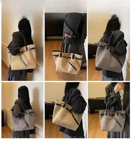 Detail view of large khaki tote bag with metal eyelet straps and black leather handles