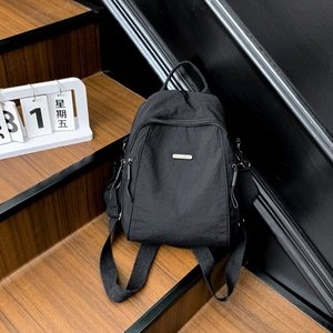 Close-up of textured black nylon fabric and rectangular metal logo on travel backpack