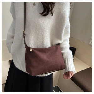 Detail of vintage matte brown suede shoulder bag with gold hardware on a white sweater