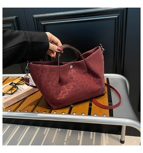 Detail of burgundy leopard print tote bag with ruched texture and metallic snap button