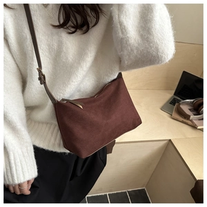 Detail of dark brown matte leather crossbody bag worn with casual knitwear