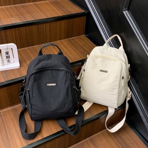 Detail view of black and beige nylon backpacks with metal logo on wooden stairs