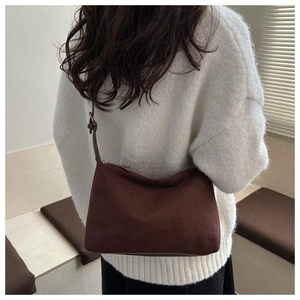 Deep brown matte underarm bag shown on model's shoulder with adjustable strap detail