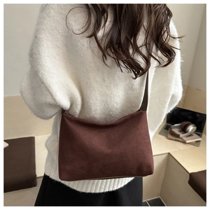 Macro shot of dark brown suede underarm bag showing velvet texture and retro strap detail