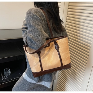 Détail du sac cabas en toile beige texturée avec anses en cuir marron et logo de marque