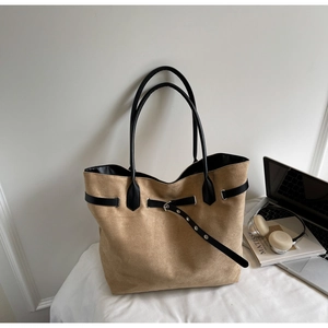 Detail der khakifarbenen Wildleder-Tasche mit schwarzen Ledergriffen und Metallschnallen
