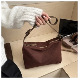 Detail of dark brown faux suede shoulder bag with smooth metal zipper on a wooden desk