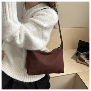 Brown frosted suede underarm bag shown on a model in a cozy indoor lifestyle setting