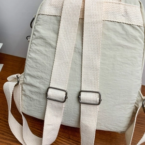 Dettaglio dello zaino in nylon crema con spallacci beige e fibbie in metallo regolabili