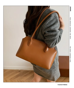 Close-up of the smooth caramel leather texture and stitching on the minimalist tote bag