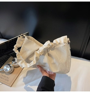 Dettaglio della borsa a mano plissettata bianco crema con finiture in oro e manico