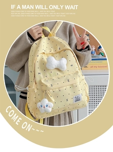 Polka dot backpack detail with plush white bow and star charm on yellow fabric