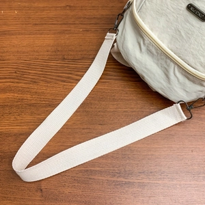 Dettaglio borsa in nylon beige con trama increspata, logo JING PIN e chiusura a moschettone