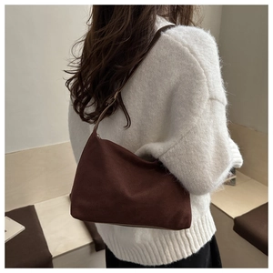 Close-up of a dark brown suede tote bag featuring minimalist matte texture and slim strap