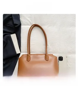 Detail view of large brown leather tote bag on white fabric with accessories
