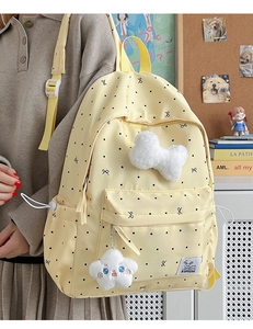 Detailed view of yellow polka dot backpack with plush bone and star charms