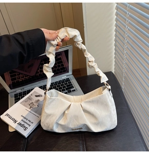 Detail of white ruched shoulder bag with cloud-like texture and metallic accents