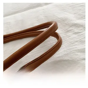 Detail of durable caramel brown leather handle with premium stitching on tote bag