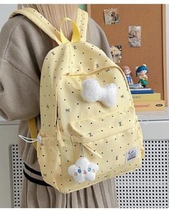 Side view of yellow polka dot backpack with plush bow and star charm in a study room