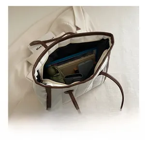 Detail view of spacious quilted tote bag showing interior storage for umbrella and books