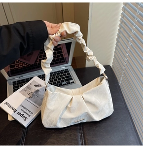 Detail of off-white pleated cloud bag with stylish silver metal buckle decoration