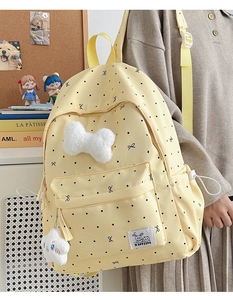 Detail of yellow polka dot backpack with plush charms and side pocket in school setting
