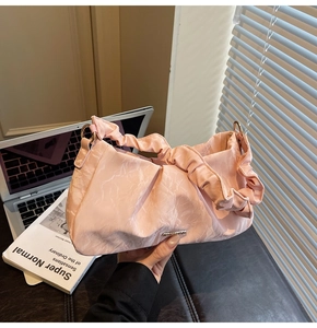 Detail of light pink ruched handbag featuring marble texture and ruffled shoulder strap