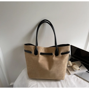 Detailed close-up of khaki suede tote bag with black handles and metal hardware