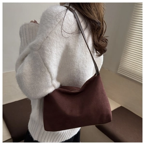 Brown suede hobo bag styled as a shoulder bag on a model wearing a white knit sweater