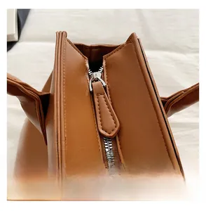 Close-up of smooth silver zipper detail on premium brown leather tote shoulder bag