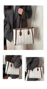 Detail view of large quilted tote bag with brown leather trim and contrast stitching