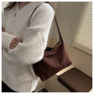 Close-up of a dark brown suede hobo bag with gold zipper and long leather strap