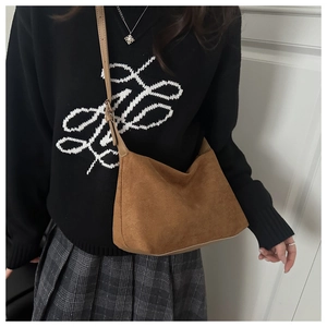 Close-up of brown suede hobo bag texture and adjustable leather strap on model