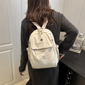 Mini beige water-resistant nylon backpack for women shown on model in a stylish indoor setting