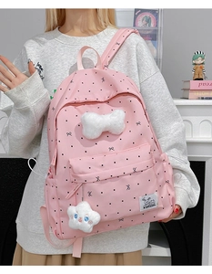 Detailed view of pink polka dot backpack with white plush bow and star pendant accessories