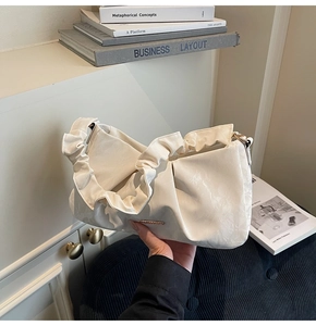 Detailed view of cream-colored ruched cloud bag with premium gold logo hardware