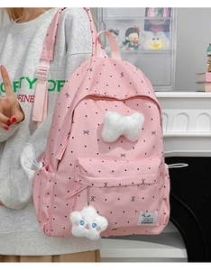 Detail of pink polka dot backpack with plush bow and cloud pendant on a model