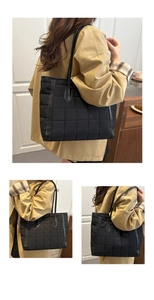 Detail view of large quilted black tote bag showing checkered pattern and leather straps