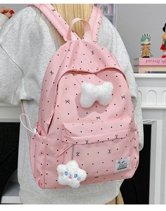 Detail of pink polka dot backpack with plush bow and star pendant in a lifestyle setting