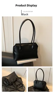Detail view of a minimalist black faux leather shoulder bag with sleek straps