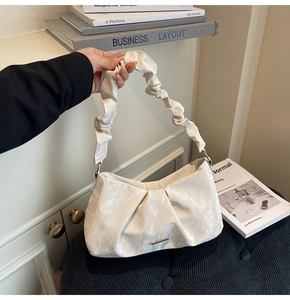 Detail of off-white pleated shoulder bag with scrunchie handle and metallic logo plaque