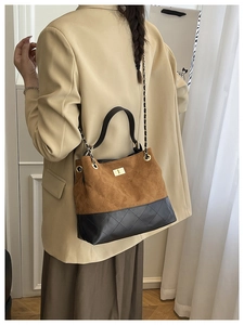 Detail of color-block bucket bag featuring quilted suede and black leather with chain strap